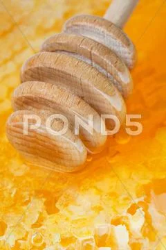 Wooden honey stick on surface of honeycomb Stock Photos