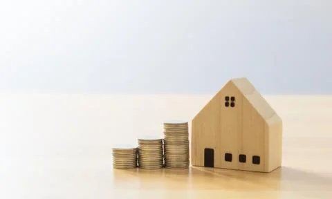 Wooden house model and stack of coins on wooden panel. saving money for a hou Stock Photos