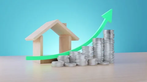A wooden house model sits beside stacks of coins and a rising green arrow on a Stock Footage 311126053