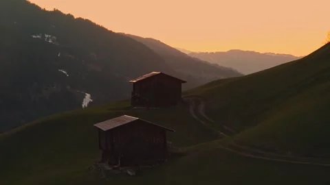 Wooden huts on rolling hills during golden hour Stock Footage 307588906