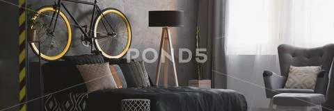 Wooden lamp standing next to bed with black sheets and many pillows standing Stock Photos