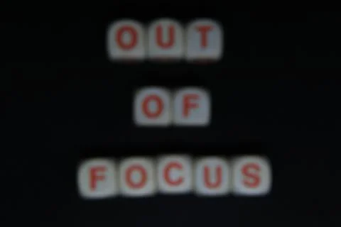 Wooden letters dices forming the writing OUT OF FOCUS on a black background Stock Photos