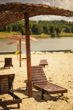 Wooden lounge and tropical umbrella at the sandy beach Stock Photos