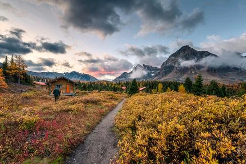 Wooden Naiset huts with rocky mountains in autumn forest at Assiniboine provi Stock Photos