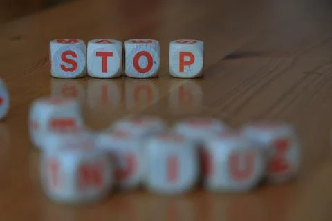 Wooden orange and white letter dice forming the word 'Stop' on wood background Stock Photos
