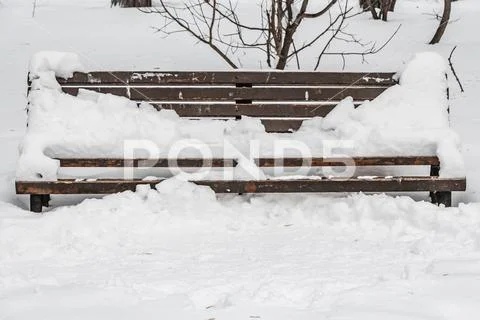 A wooden painted brown color beautiful bench with black wrought-iron legs stands Stock Photos