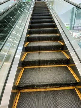 A wooden parallel rectangle building with a close-up yellow-lined escalator.. Foto stock