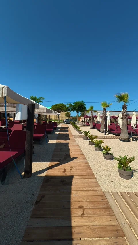 Wooden path winds through sunlit beach scene. Trani Ammouda, Greece. Vertical Stock Footage 339629155