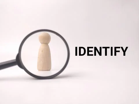 A wooden peg doll is centered within a magnifying glass next to the black t.. Stock Photos