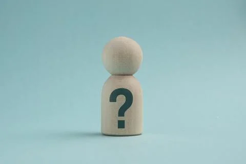 Wooden peg doll with a question mark on its body against a blue background,.. Stock Photos