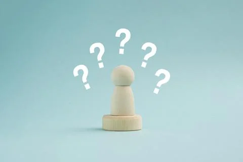 Wooden peg doll surrounded by multiple white question marks on a blue backg.. Stock Photos