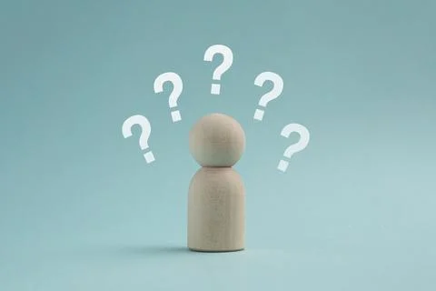 Wooden peg doll surrounded by multiple white question marks on a blue backg.. Stock Photos