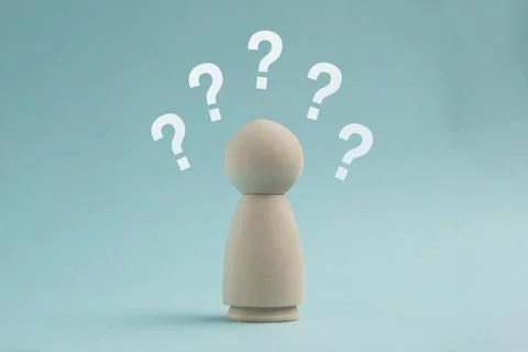 Wooden peg doll surrounded by multiple white question marks on a blue backg.. Stock Photos
