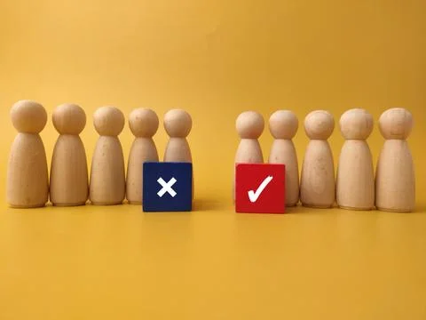 Wooden peg figures are split into two groups, separated by wooden blocks fe.. Stock Photos
