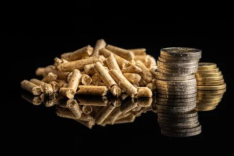 Wooden pellets and euro coins on black background. Biomass Stock Photos