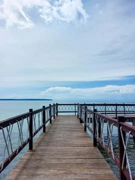 Wooden Pier and Dramatic Clouds Over Calm Ocean Water. Stock Photos