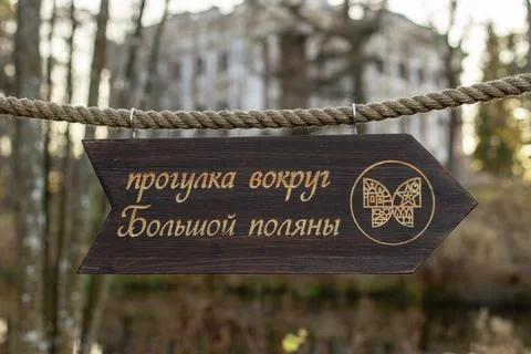 Wooden pointer in the form of an arrow on an old thick rope in the forest Stock Photos