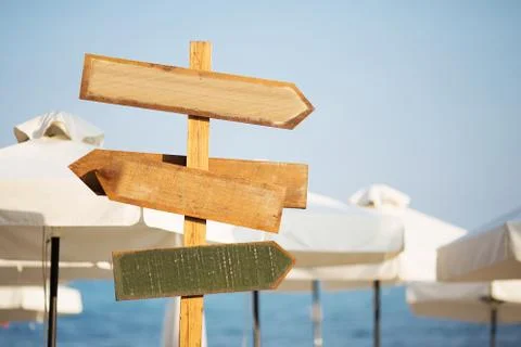 Wooden pointer post with copy space at the beach. arrows on a guidepost point Stock Photos