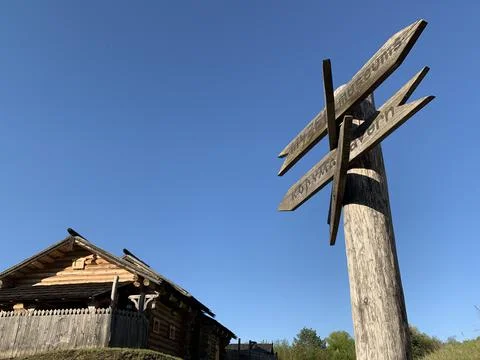 Wooden post with many pointers. There are different signs at the crossroads.  Stock Photos