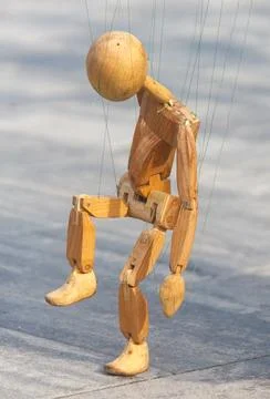 Wooden puppet is suspended from a string Stock Photos