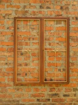 Wooden rectangular frame with a metal grill on the background of an old brick Foto stock