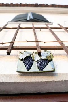 Wooden rectangular plaque with ceramic grape pattern hanging on fence Stock Photos