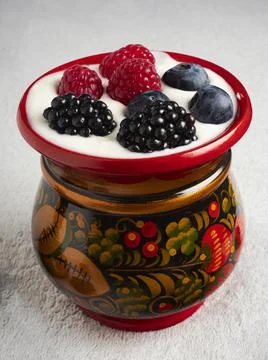 Wooden red patterned cup with berries and yogurt inside Stock Photos