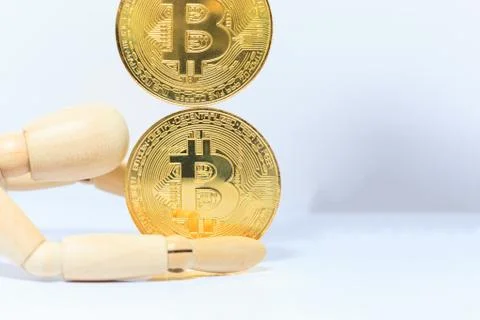 Wooden robot model stops falling Bitcoin cryptocurrency token on white backgr Stock Photos