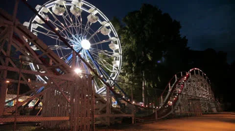 Wooden Roller Coaster Flys through Ferris Wheel In Background Stock Footage 26659572