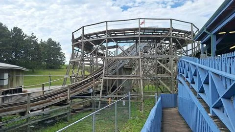 Wooden roller coaster structure stands in an amusement park. Stock Photos