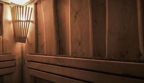 Wooden sauna interior features rustic log walls and warm lamp lighting. Stock Photos