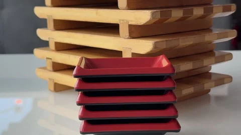 Wooden serving boards and red sauce dishes for sushi presentation on white table Stock Footage 346183780