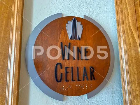 A wooden sign that states Wine Cellar outside a door of a condo building. Stock Photos