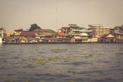 Wooden slums on stilts on the riverside of Chao Praya River in Bangkok, Thail Stock Photos