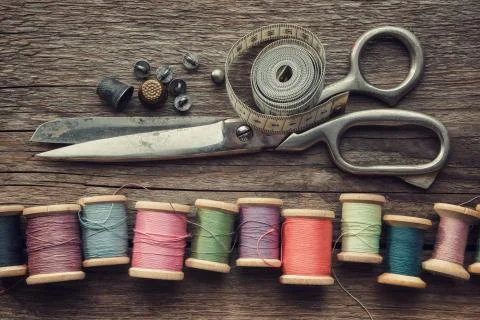 Wooden spools of threads, tailoring scissors, thimbles, measuring tape. Stock Photos