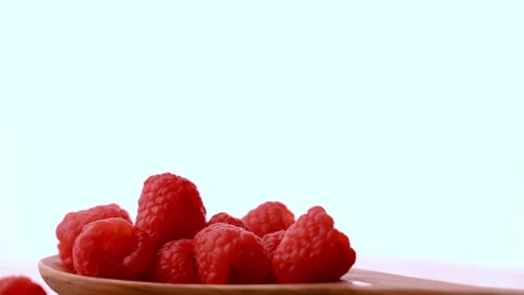 Wooden spoon with Fresh raspberries falling and splashing on the kitchen tabl Stock Footage