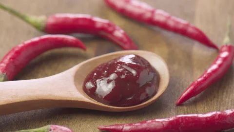 Wooden spoon of hot pepper paste among fresh chili peppers Video stock 312084886