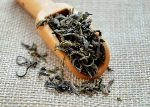 A wooden spoon with leaf tea lies on a jute bag. Stock Photos