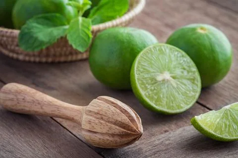 Wooden squeezer and lime on table Stock Photos