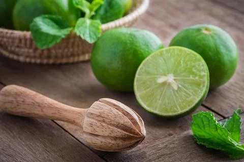Wooden squeezer and lime on table Stock Photos
