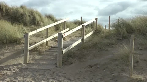 Wooden steps through sand dunes moving grasses coastal path.mp4 Stock Footage 49472134