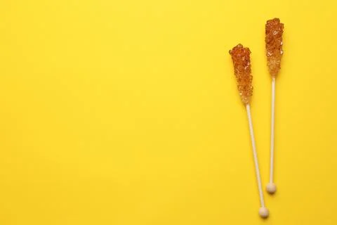 Wooden sticks with sugar crystals and space for text on yellow background, fl Stock Photos