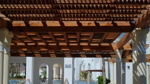 The wooden structure of the gazebo is supported by smooth cylindrical white colu 库存影片 237448846
