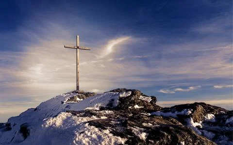 Wooden summit cross on the mountain peak with cloudy clear sky Stock Photos