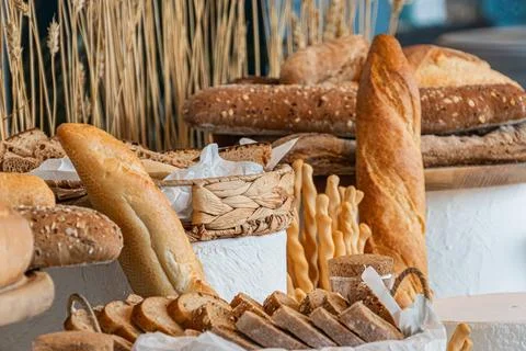 Wooden surface holds a selection of bread loaves, including baguettes, sourdo 스톡 사진