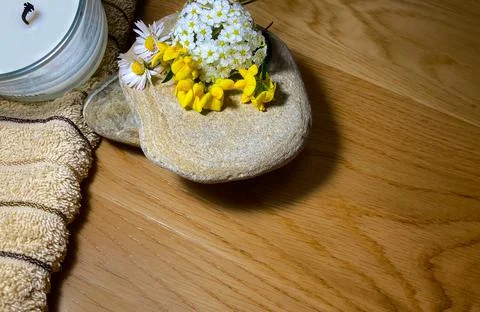 On a wooden surface lies two flat stones, on which are beautiful flowers Stock Photos