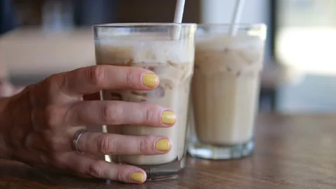 On a wooden table are two full glasses with a plant-based milkshake and ice Stock Footage 220042940