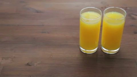 On the wooden table are two glasses of orange juice. The camera moves from le Stock Footage 89157446
