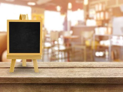 Wooden table with blurred bokeh restaurant background with blackboard menu an Stock Photos