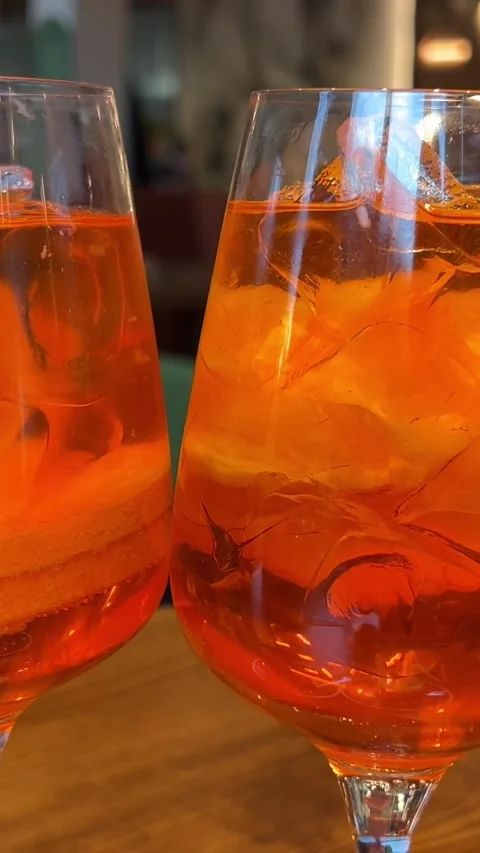 Wooden table desserts Coco and Rose jelly cheesecake and two glasses of Aperol Stock Footage 316089246